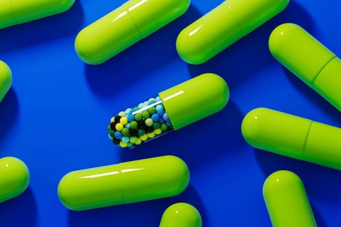 Colorful capsules and pills are scattered on a vivid blue background, showcasing various shapes and