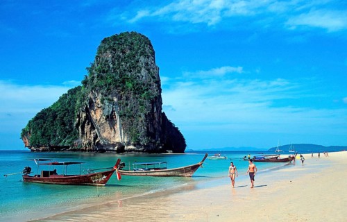 Rocks in the sea, people and longtail boats on Pranang Cave beach, two years in front of the