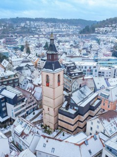 Old tower, Urban panorama with church tower and snow-covered roofs in a hilly winter landscape,