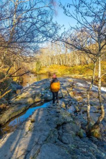 Hiker standing on rocks admiring the baias river in zaldibartxo pool, gorbeia natural park, basque