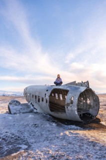 Woman sitting on the plane of Solheimasandur concentrated in meditation in Iceland