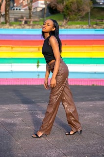 Vertical portrait of a sensual african woman posing standing on an urban space with colorful stairs