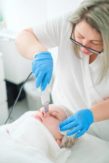 An esthetician cosmetologist uses ultrasonic facial cleansing to deeply exfoliate and refresh the