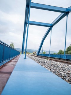 View of blue iron bridge and rails in the distance a train, track construction, rail delivery for