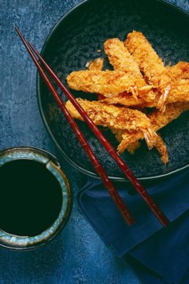 Shrimp in tempura, deep fried, on a black plate, with soy sauce, close-up, top view, no people