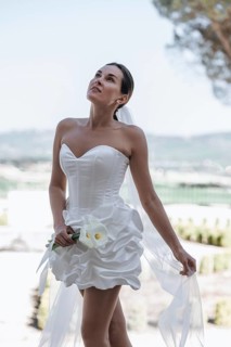 A stunning bride in a strapless gown stands elegantly in the garden of an ancient villa in Treia,