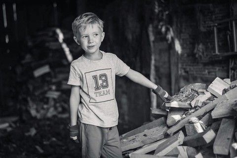 Little boy working in a shed with wood