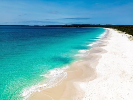 A picturesque view of a tranquil beach with clear turquoise water meeting a pristine white sandy