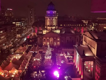 View from above of Christmas market at Gendarmenmarkt at night with vivid colors and glowing