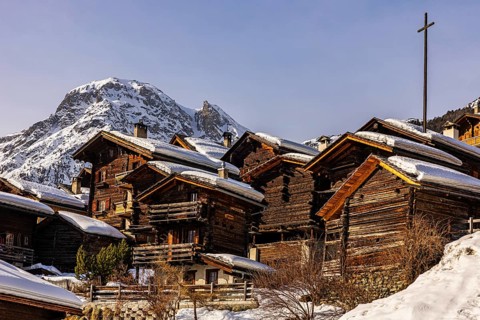 Snow-covered old farmhouses, large wooden cross, historic town center, Grimentz, Val d'Anniviers,