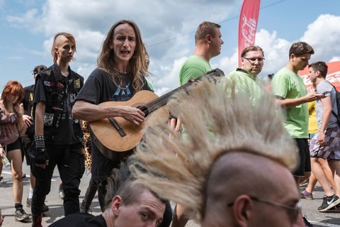 KOSTRZYN NAD ODRA, POLAND - AUGUST 1, 2019: Singing man with guitar passing near men with Iroquois