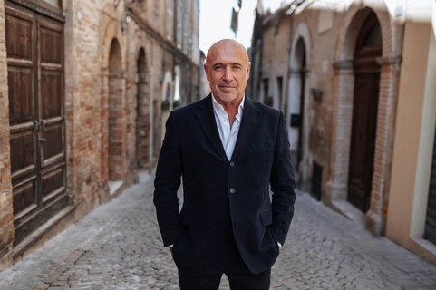 Confident man in a black suit stands on a cobblestone street, showcasing a business portrait theme