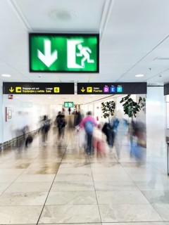 A dynamic scene captures the blurred motion of travelers in an airport corridor under signage,