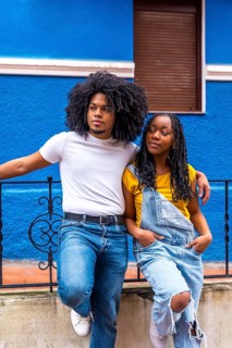 Vertical portrait of a distracted cool african couple embracing from the shoulder leaning on a