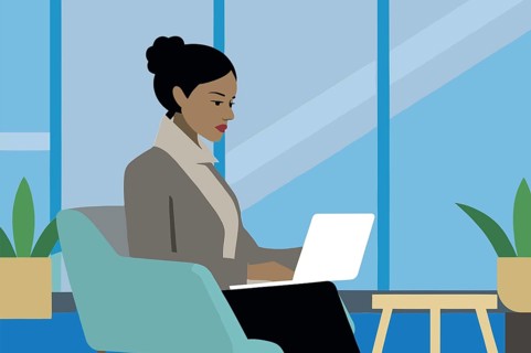 A businesswoman concentrates on her laptop while seated in a stylish chair in a bright office space