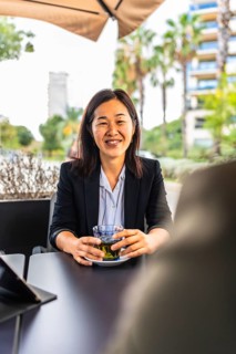 Vertical portrait of a happy successful chinese businesswoman drinking tea sitting in a cafeteria