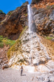 Female hiker enjoying the refreshing spray of rinka waterfall in the picturesque logarska dolina