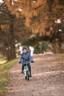 Six years old boy rides bicycle from the hill in the park