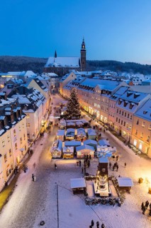 The snow-covered Christmas market with St Wolfgang's church seen from the town hall tower,