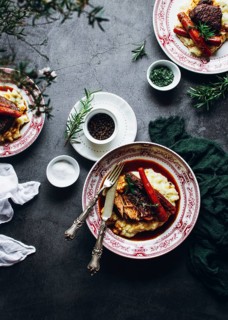 A beautifully presented rustic meal featuring mashed potatoes topped with tender meat and