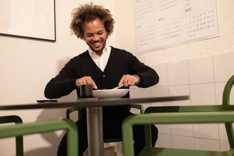 A man enjoys a casual lunch in a modern coworking space in Barcelona. The setting is designed for
