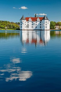 Glücksburg moated castle under a blue sky with white clouds, reflection in the castle pond,