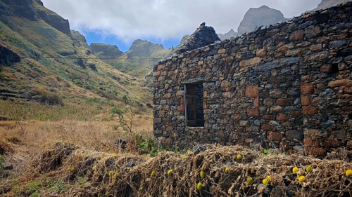 Abandoned stone house in the midst of a mountainous landscape with clouds in the sky, hiking, lost