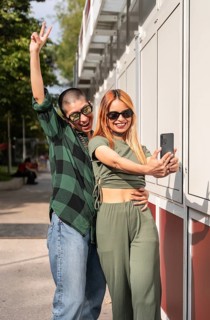 A cheerful Colombian lesbian couple takes a selfie together, smiling and posing playfully. Their