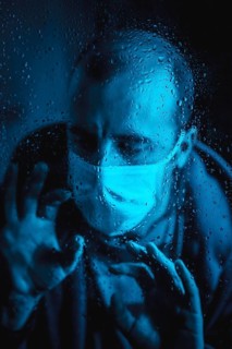 A young man wanting to leave home in the quarantine of the covid 19 one rainy night with a mask