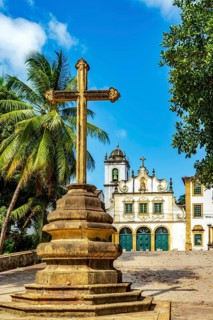 Facade of historic baroque church with stone crucifix in front in Olinda, Pernambuco, Brazil,