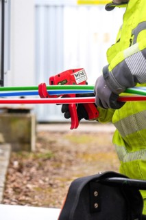 Person in protective clothing at work with coloured cables and tools, Wend Glasfasermontage during