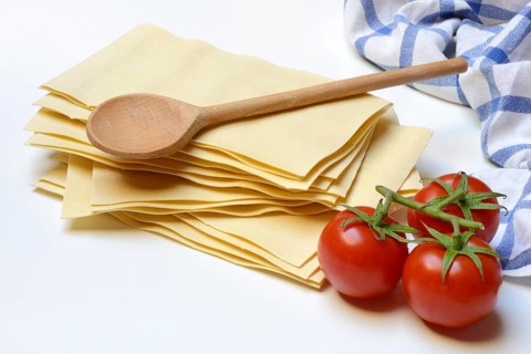 Lasagna, dried lasagna leaves with tomatoes and cooking spoon