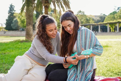Romantic young lgtbiq+ couple, sitting on a picnic blanket in a park, sharing a moment while