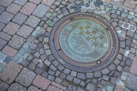 Manhole cover with city coat of arms and wild boar figure, inscription, year, 1368, paving stones,
