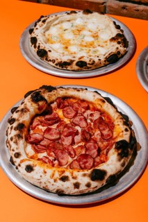 Wood-fired Four Meats pizza with smoked pork, salami, sausages, chicken, mozzarella, and tomato