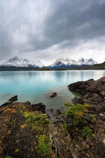 Cloudy mountain range Cuernos del Paine, shore of the blue lake Lago Pehoe in the evening light,