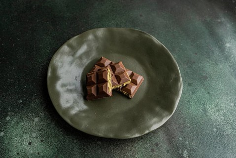 Top view of a homemade milk chocolate bar filled with rich pistachio nut paste, presented on a
