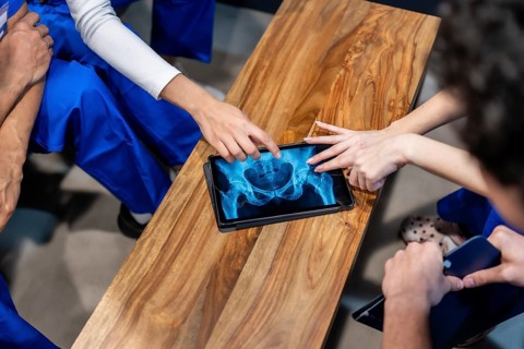 Healthcare professionals in scrubs are analyzing a hip and pelvis x ray image on a digital tablet,