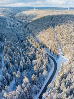 Snowy landscape with a road leading through a dense forest, peaceful winter atmosphere, Bad