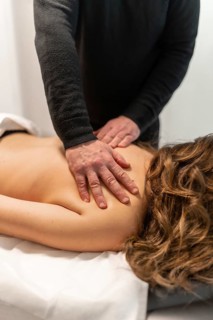 Masseur applying therapeutic pressure and movement on a client's back and shoulders, providing