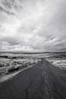 Deserted country road in Ireland, Atlantic Ocean on the horizon, barren landscape, symbolic photo
