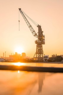 A crane rises in the light of the rising sun in the harbour area, Hamburg, Germany