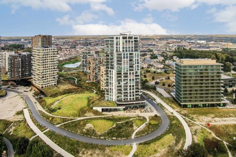 Aerial view of a contemporary urban area featuring high-rise buildings nestled among lush green