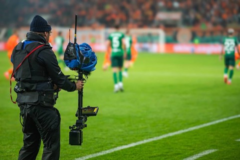 Cameraman behind playing field during soccer match.
