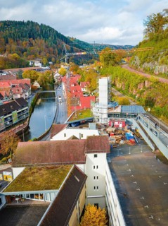 City view with river, buildings and construction crane, surrounded by autumnal landscape, extension