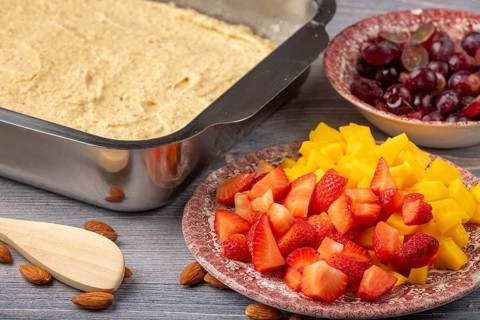 Dough in a mold next to sliced fruit