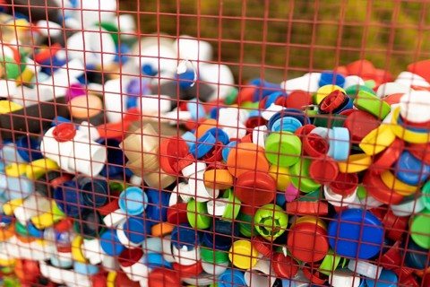 A vibrant assortment of plastic bottle caps collected in a basket, emphasizing the importance of