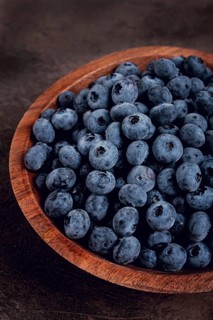 Fresh blueberries, in a wooden bowl, on the table, top view, close-up, no people