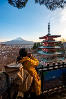 Tourist photographs five-story pagoda of a Shinto shrine, Chureito Pagoda, with views of