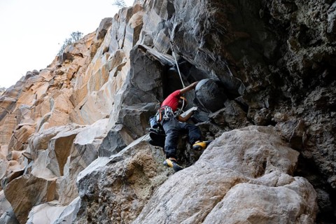 A climber expertly navigates a rugged rock face, showcasing skill and determination in traditional